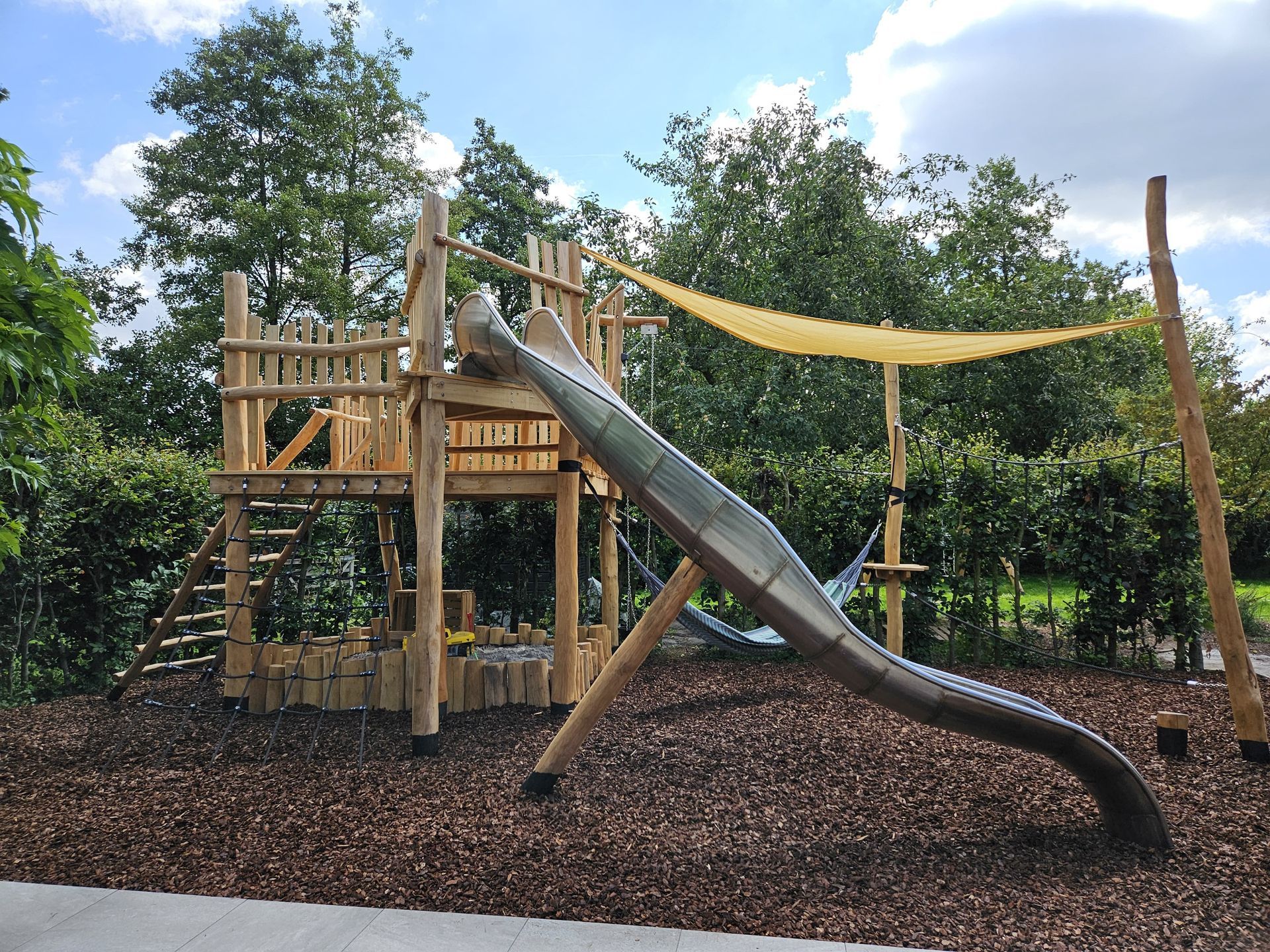 Een houten boomhut met glijbaan en trap