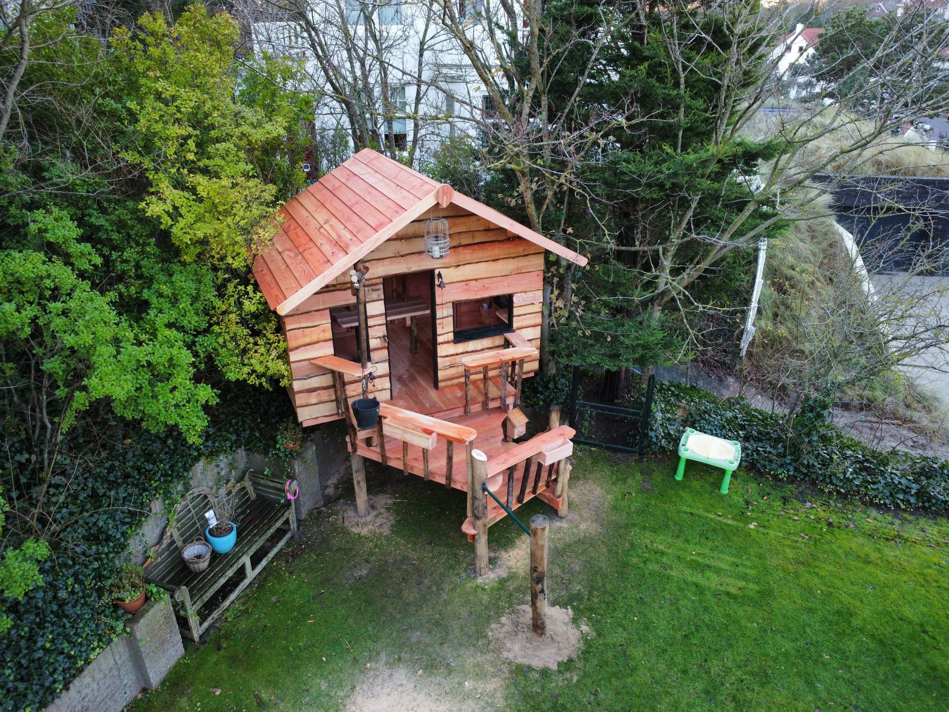 Een luchtfoto van een houten boomhut in een achtertuin.