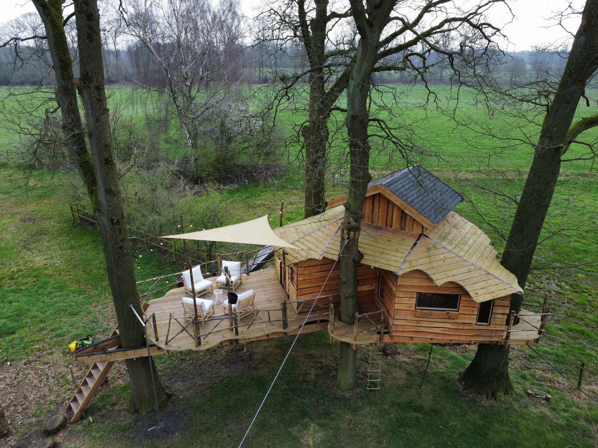 Een luchtfoto van een boomhut midden in een veld.