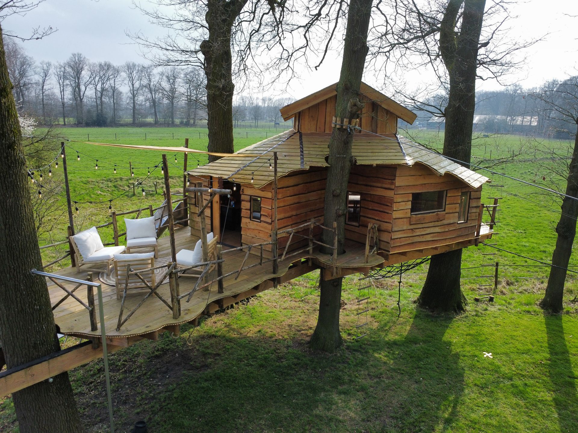 Een luchtfoto van een grote boomhut midden in een veld.