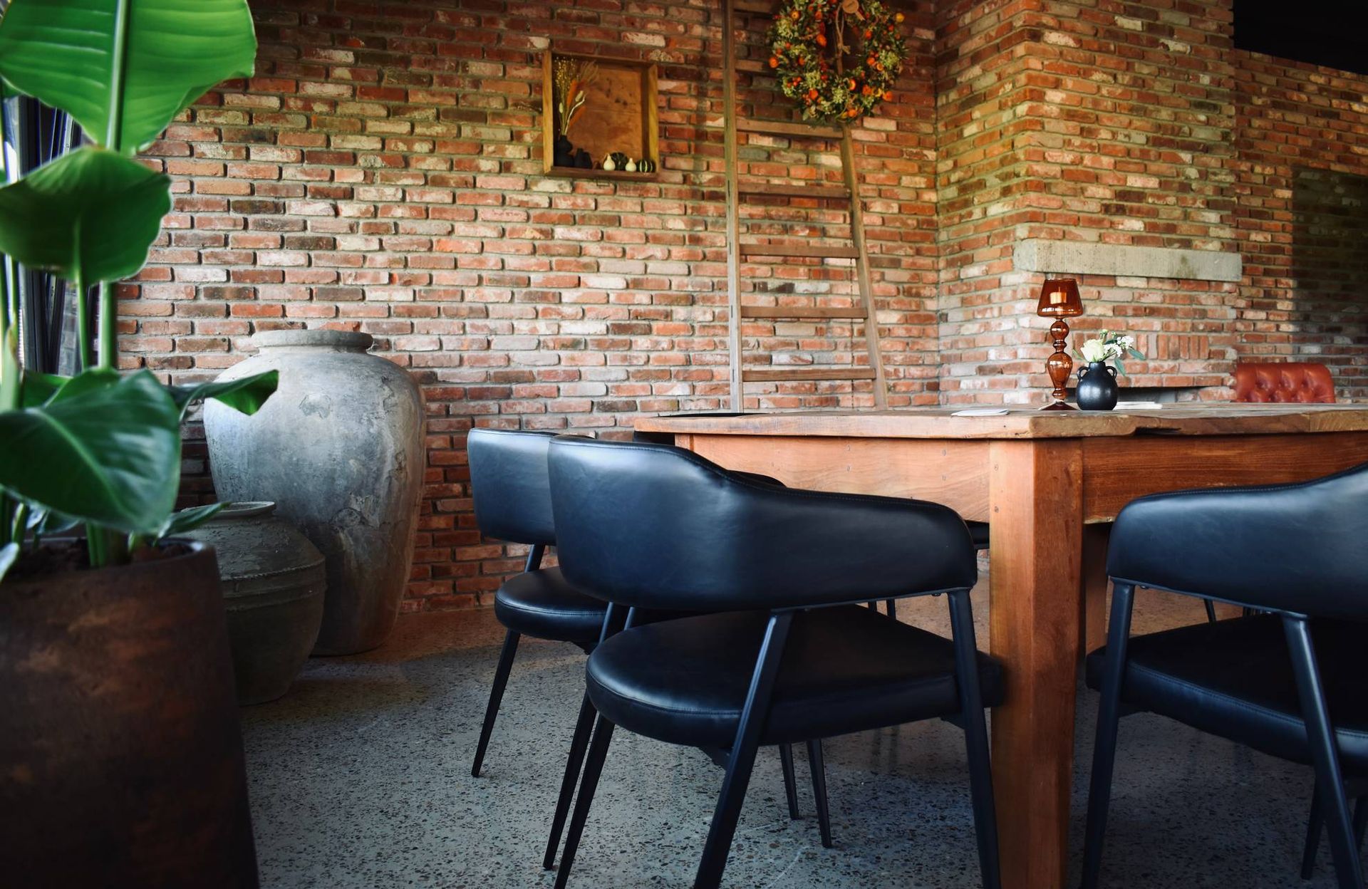 Een eetkamer met een tafel en stoelen voor een bakstenen muur.