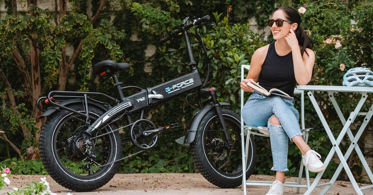 A woman is sitting at a table next to an electric bike.