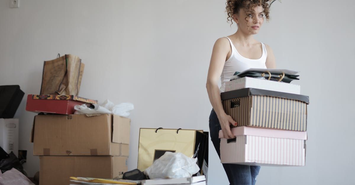 A woman is carrying a stack of boxes in a room.