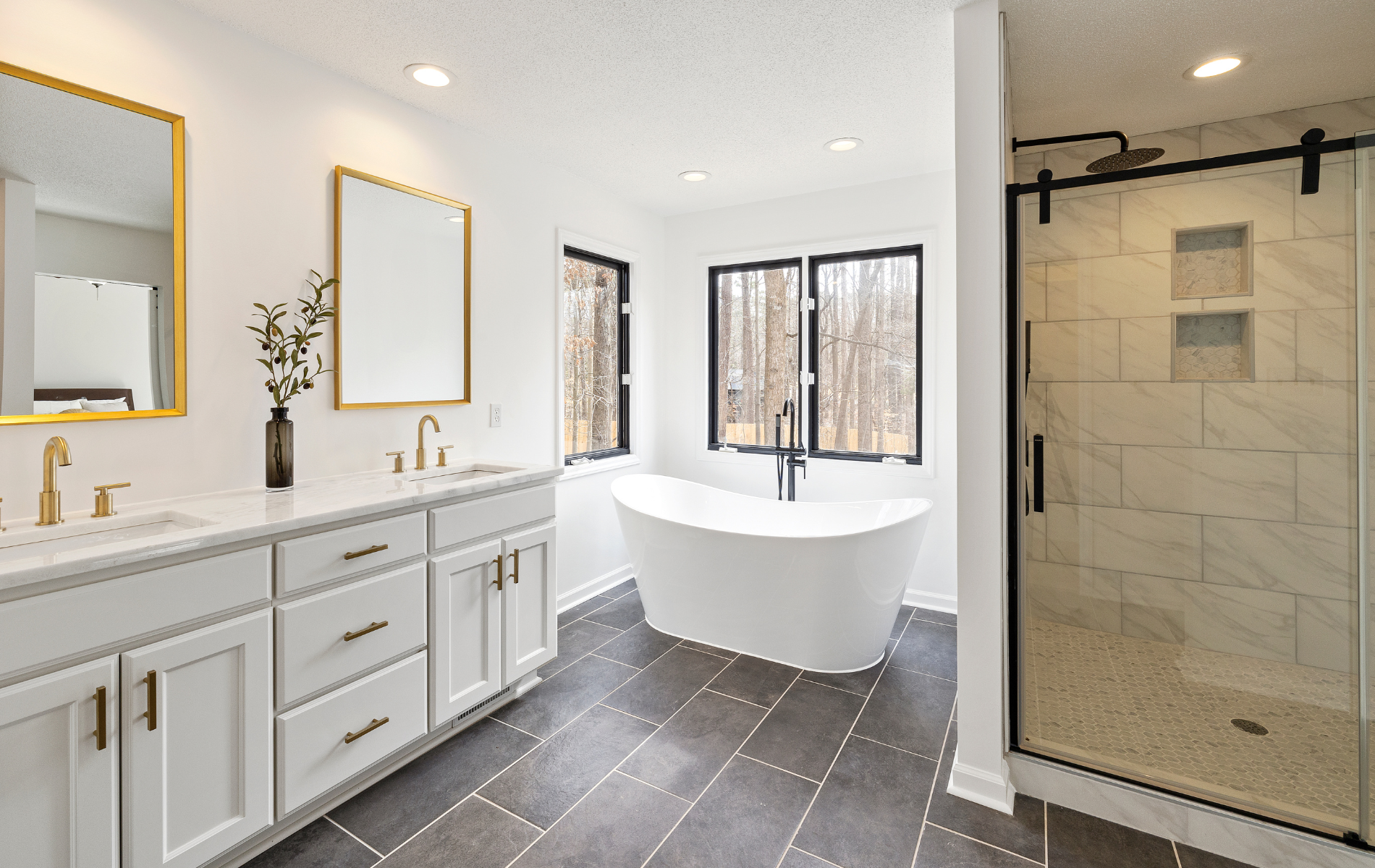 Bright white bathroom with a freestanding tub, dark windows, and a glass shower.