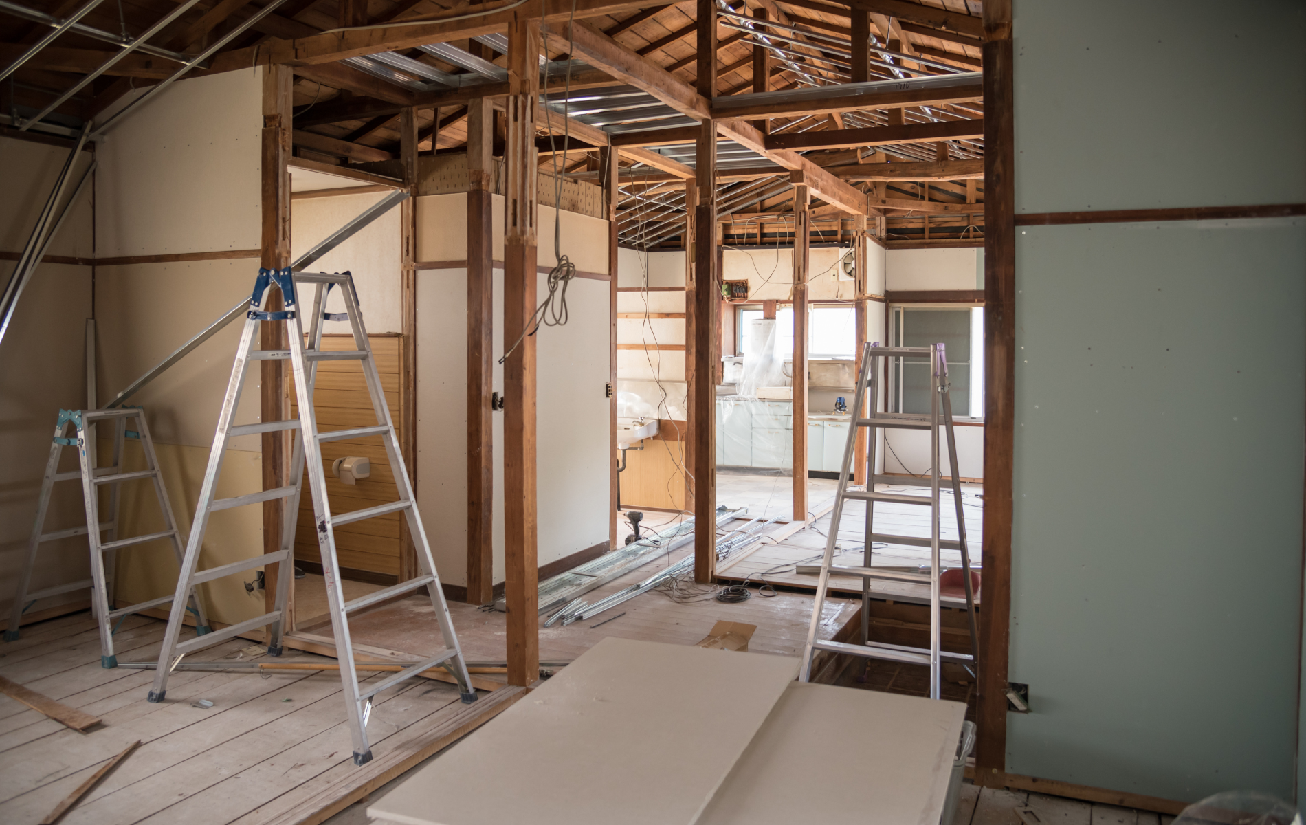 Interior house under renovation with wood framing, ladders, and exposed walls.