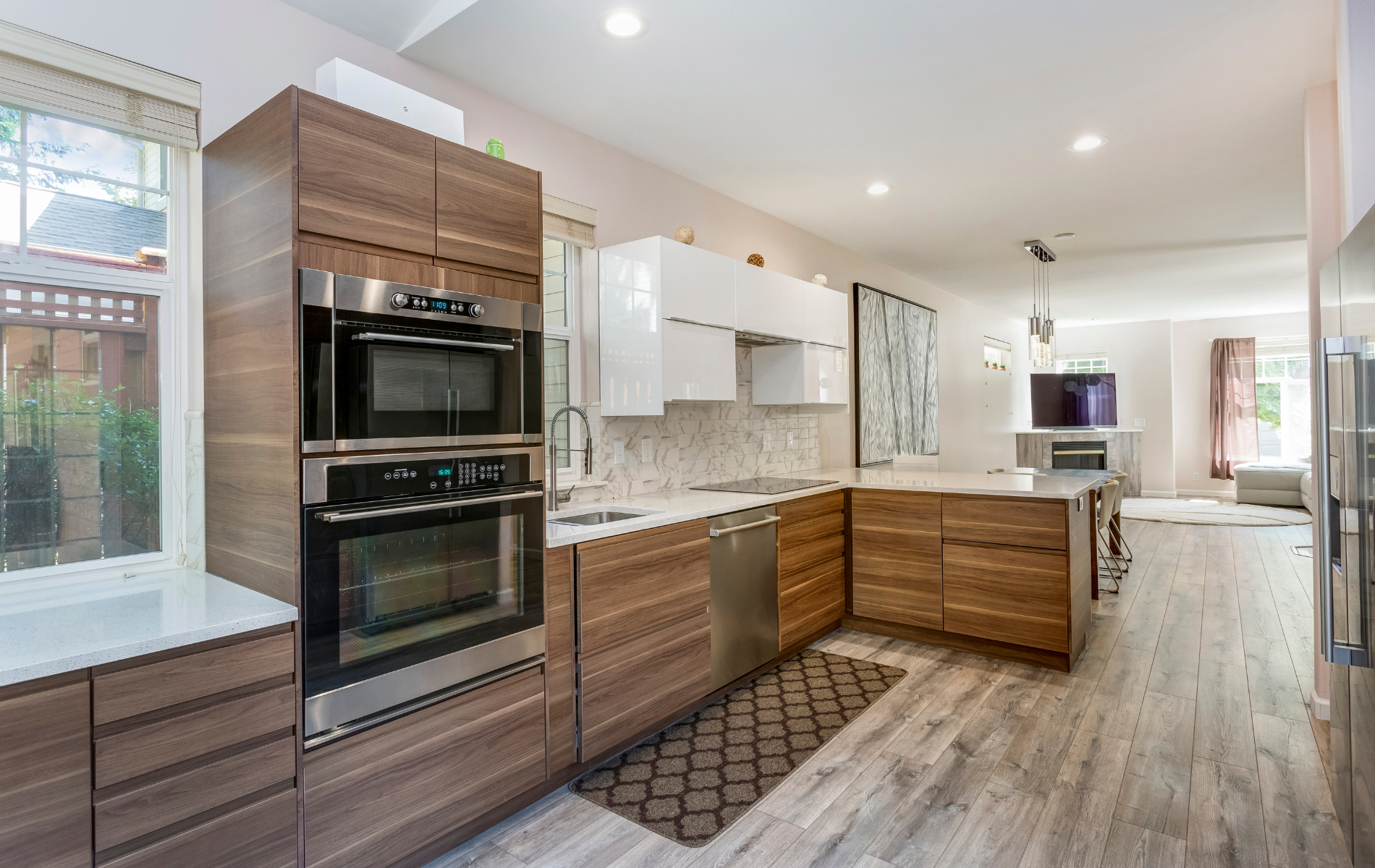Modern kitchen with wood cabinets, stainless steel appliances, and island; view to living room.