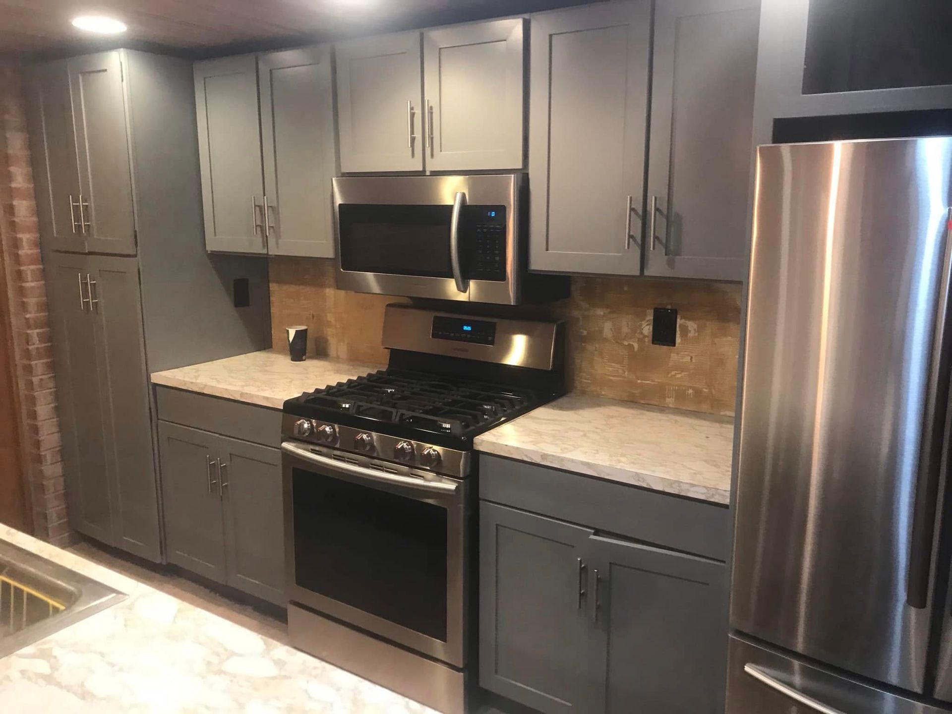 Modern kitchen with gray cabinets, stainless steel appliances, and granite countertops.