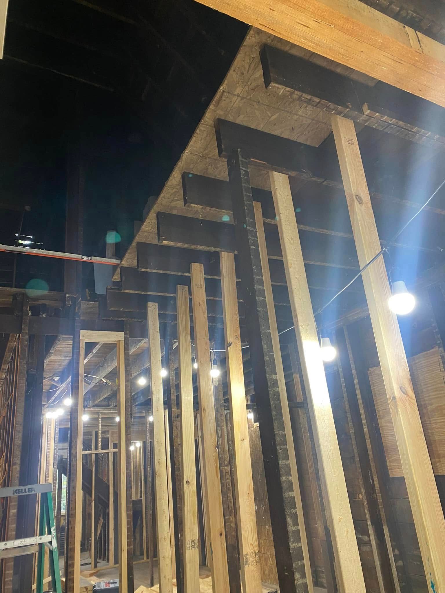 Row of illuminated wooden frames under construction at night, viewed from below.