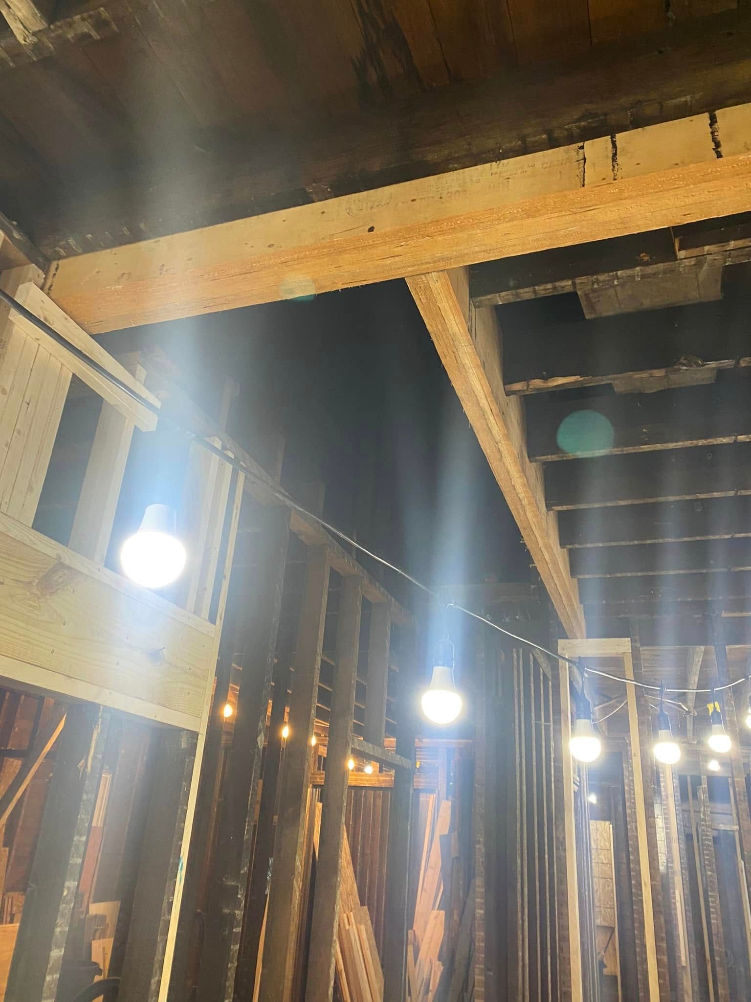 Indoor wooden beams and hanging lights in a rustic interior with high ceiling