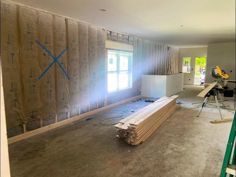 Renovation room with stacked lumber, window light, and a miter saw on a stand