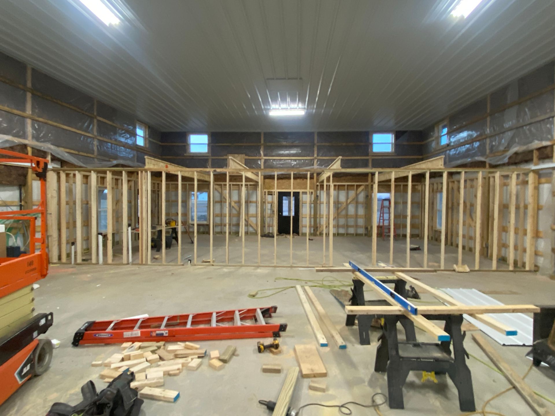 Back patio under construction with wooden posts, covered grill, and grassy yard beside a house