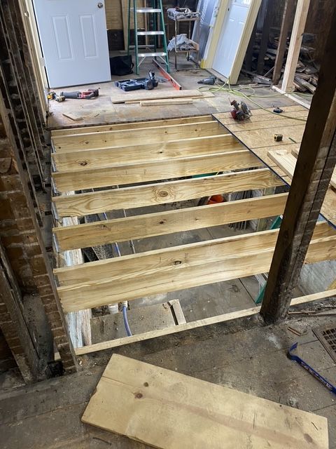 Partially built roof truss with Tyvek wrap and a wood plank on a house under construction