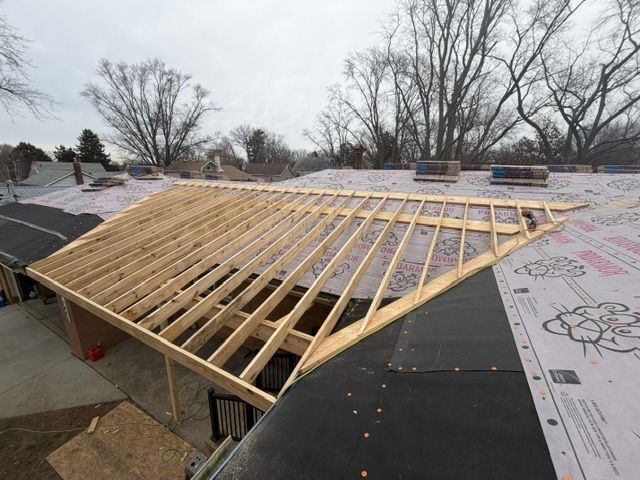 Front porch under construction with ladders, tools, and exposed wooden roof framing