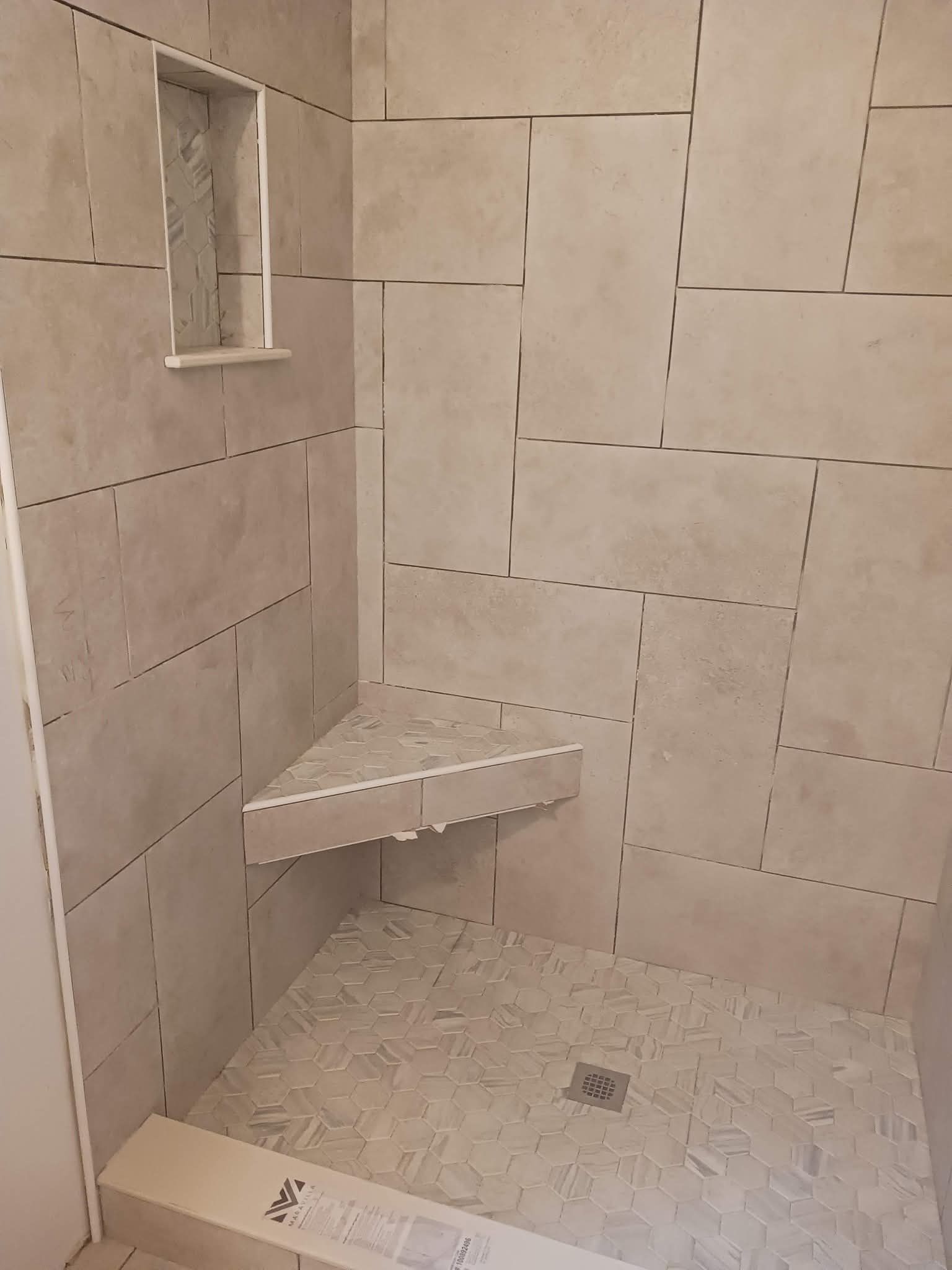 Shower interior with tiled walls, corner seat, and built-in shelf.
