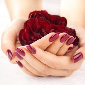 a lady's nails painted with dark red nail polish