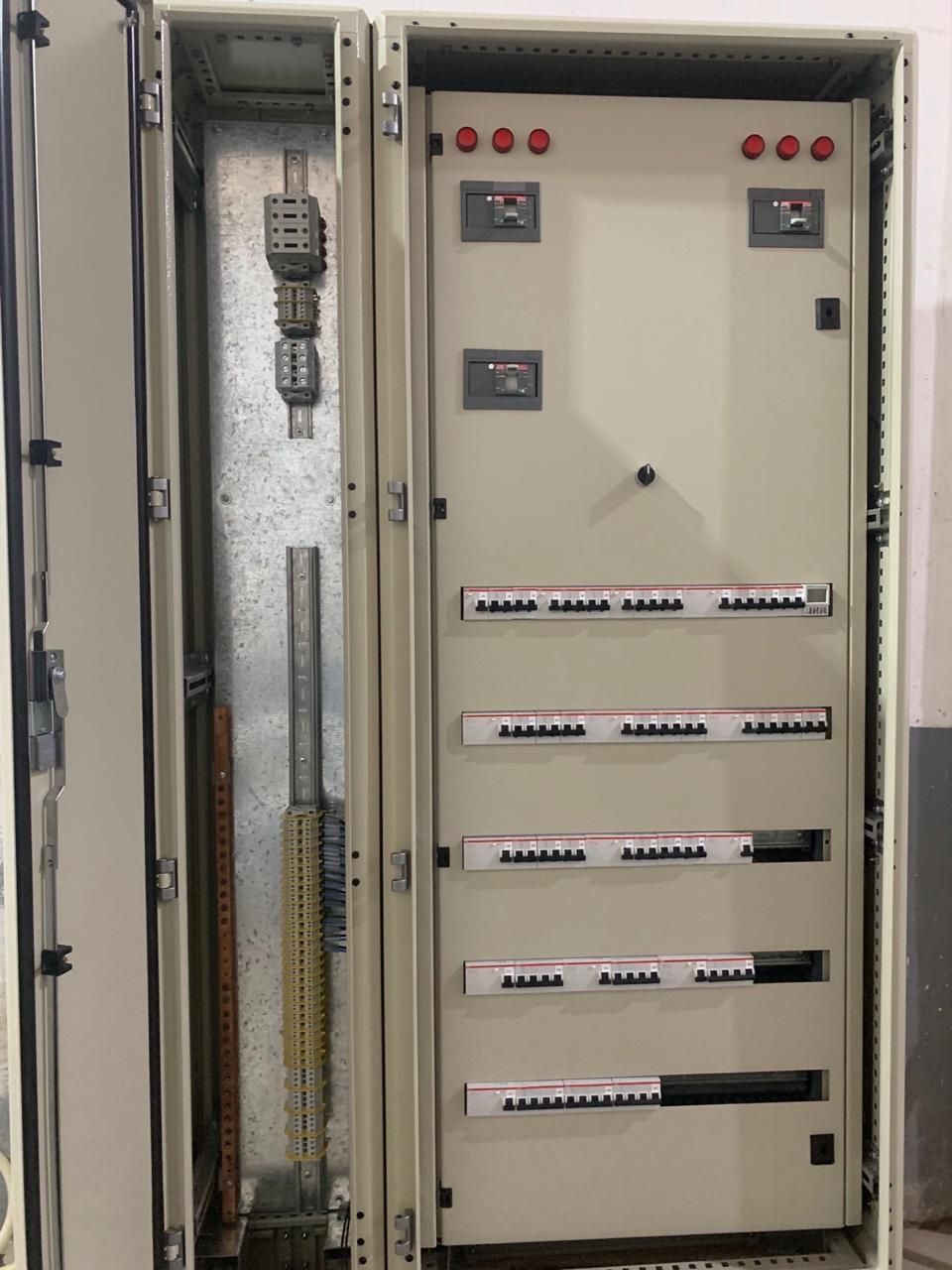 Panel eléctrico abierto con varios componentes, incluidos disyuntores y bloques de terminales.