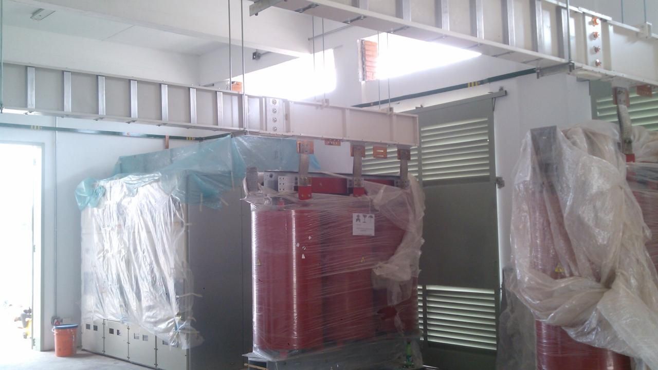 Maquinaria de gran tamaño de color rojo y blanco envuelta en plástico dentro de un edificio con estructura de metal.