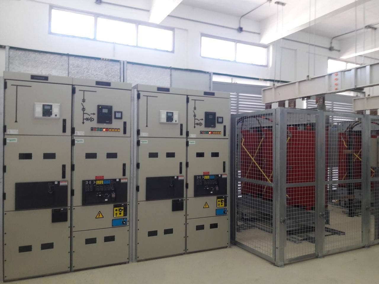 Armarios de distribución eléctrica en cuarto de servicio, con jaula protectora que contiene equipos de color rojo.