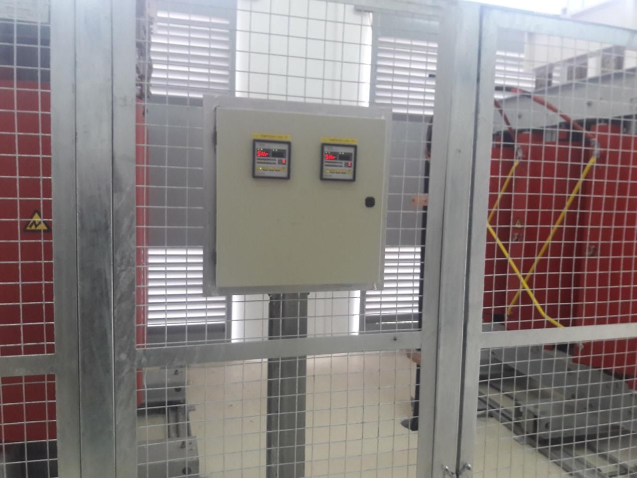 Caja metálica con cuadro de control y dos contadores, detrás de alambrada.