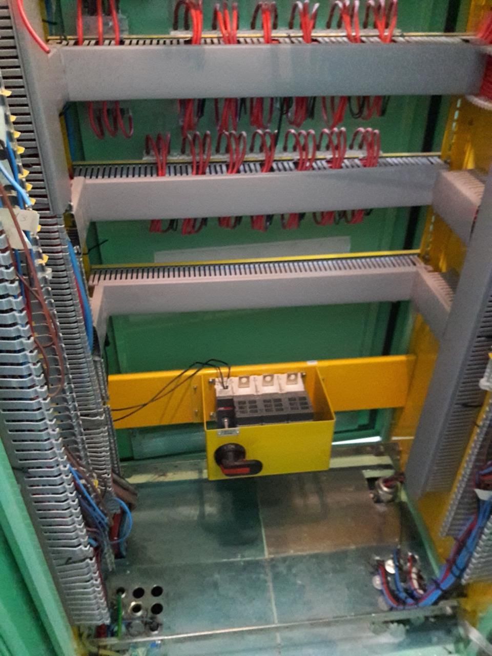 Gabinete eléctrico verde con cables, interruptores y terminales.