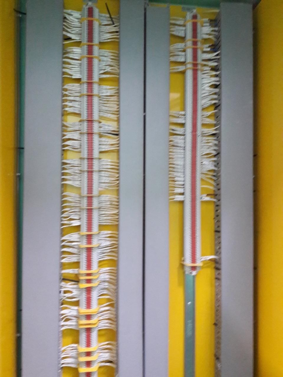 Dos paneles verticales con filas de cables blancos y rojos, sobre un fondo amarillo.