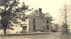 A two-story funeral home with porch and trees in the yard.