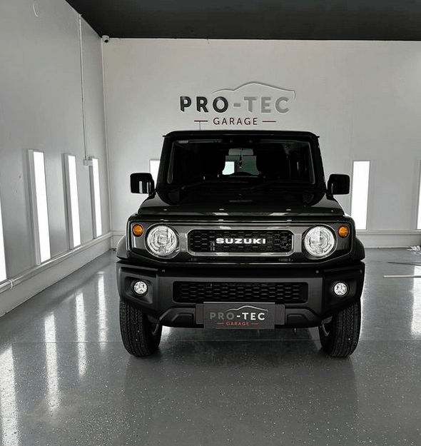 A black suzuki suv is parked in a garage for ceramic coating