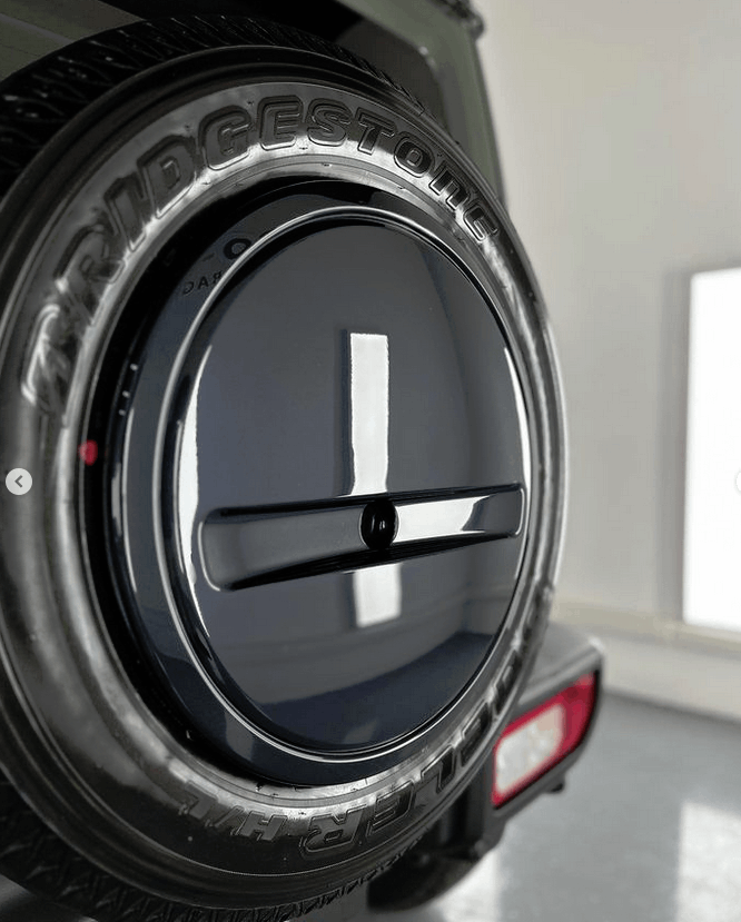 A black suzuki suv is parked in a garage for ceramic coating on spare tire cover