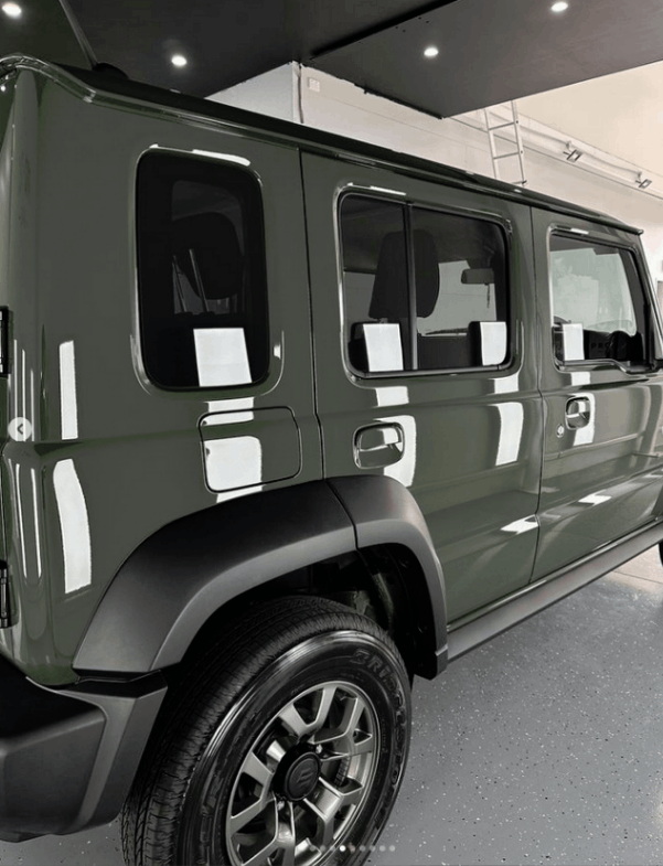 A black suzuki suv is parked in a garage for ceramic coating on side of car.