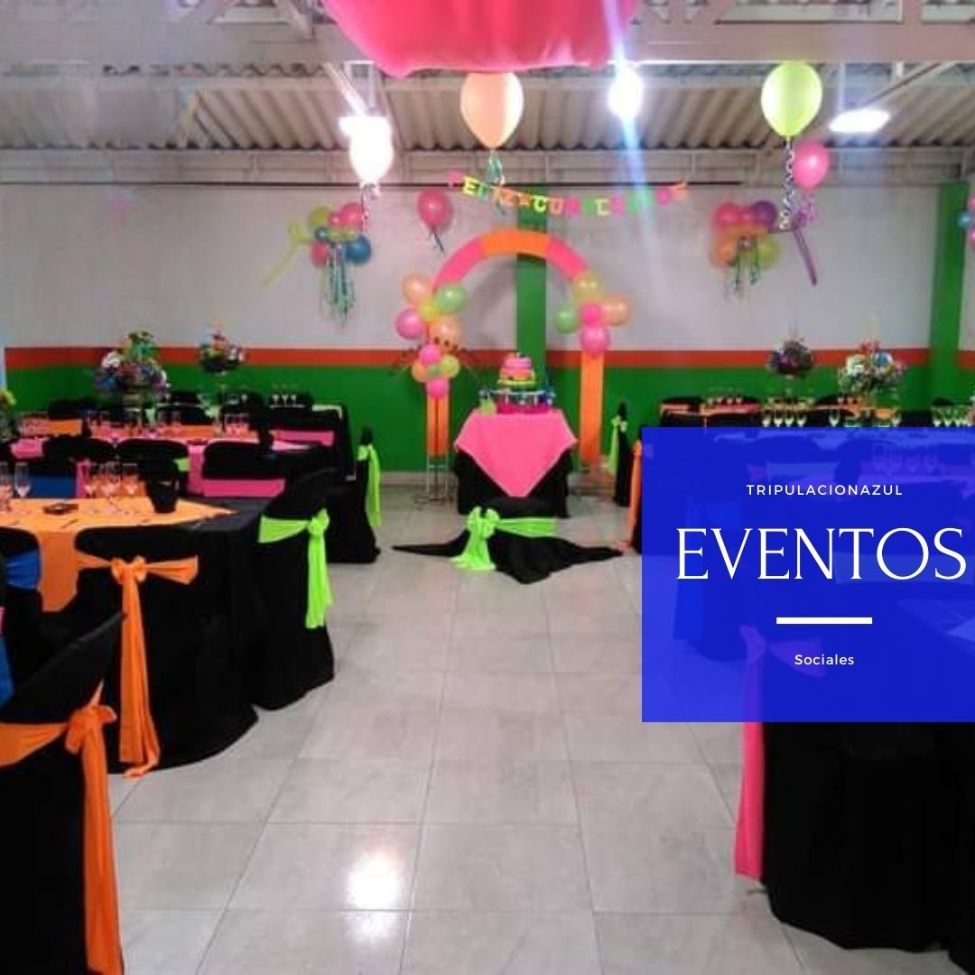 Salón de eventos decorado con globos y mesas coloridas.