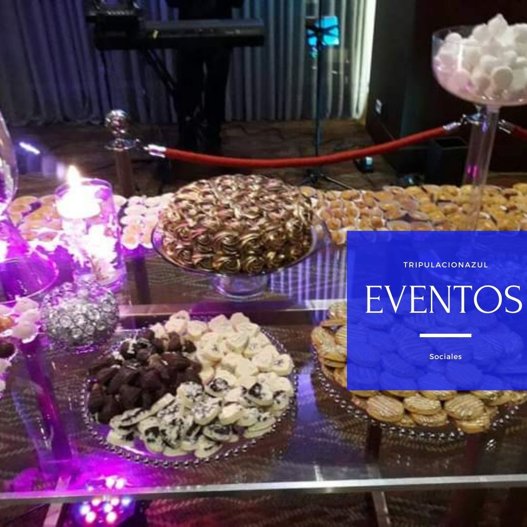 Mesa de postres con diversos dulces, entre ellos tarta y chocolates, en un evento.