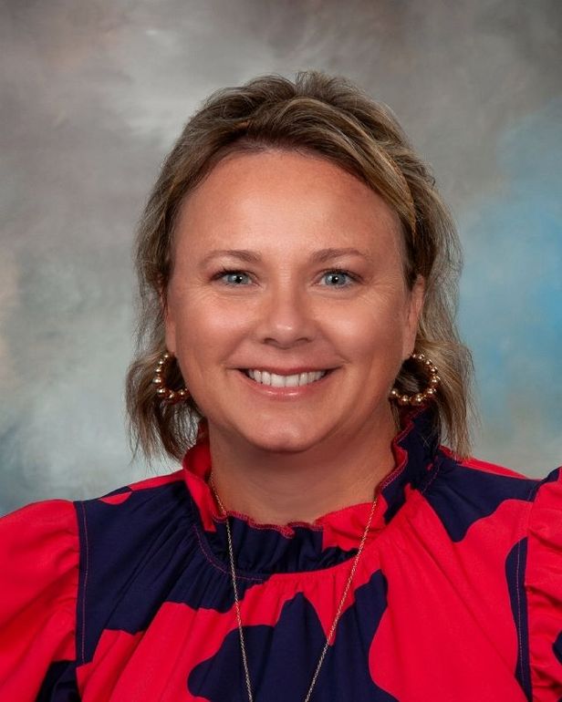 a woman wearing a red and blue shirt and earrings smiles for the camera