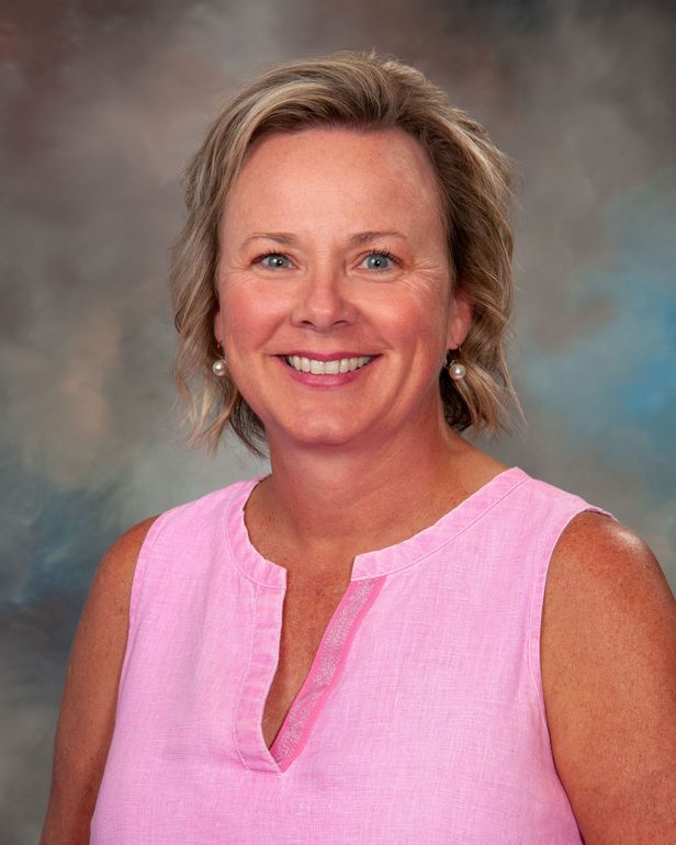 a woman wearing a red and blue shirt and earrings smiles for the camera
