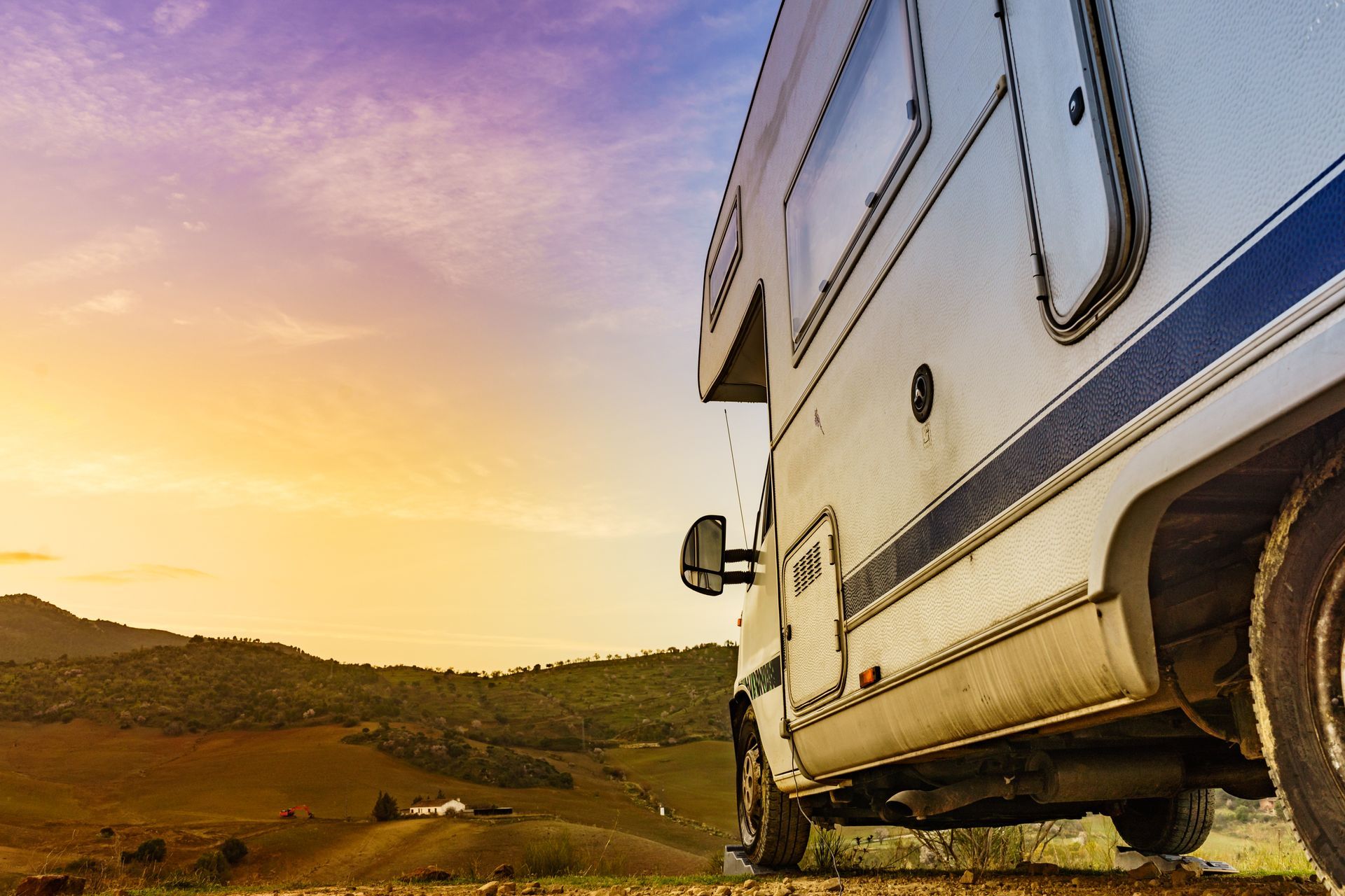 A rv is parked on the side of a dirt road.