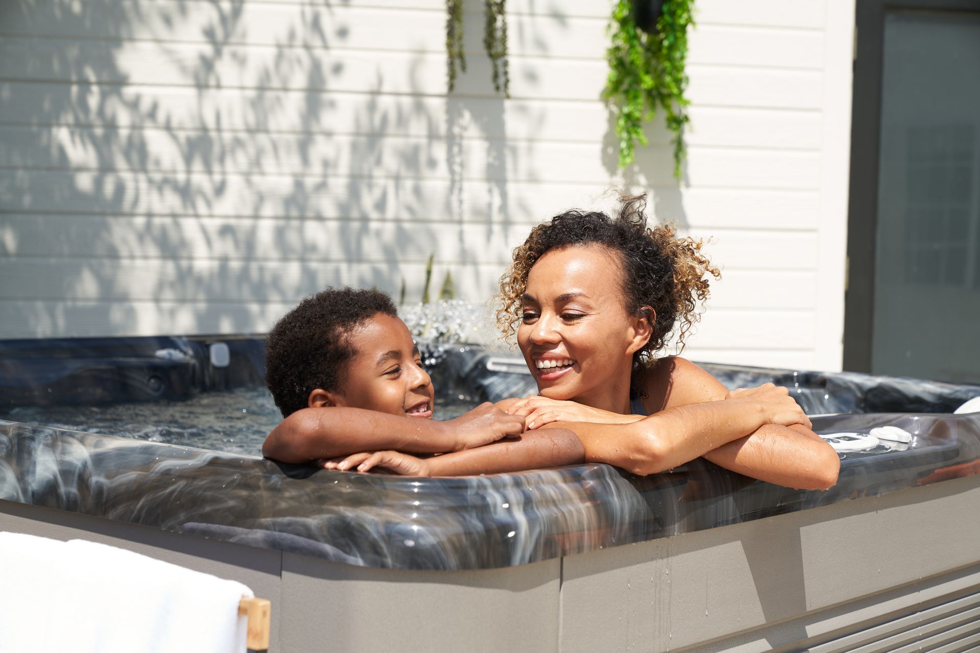 Elderly couple toasting champagne in a hot tub, smiling, outdoors.