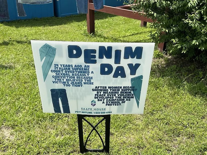 Sign for Denim Day in a grassy area. It states it started in Italy in response to a rape conviction