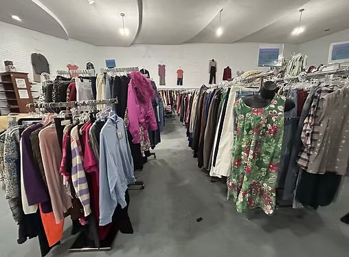 Clothing racks in a brightly lit retail space, featuring a wide array of garments and mannequins.