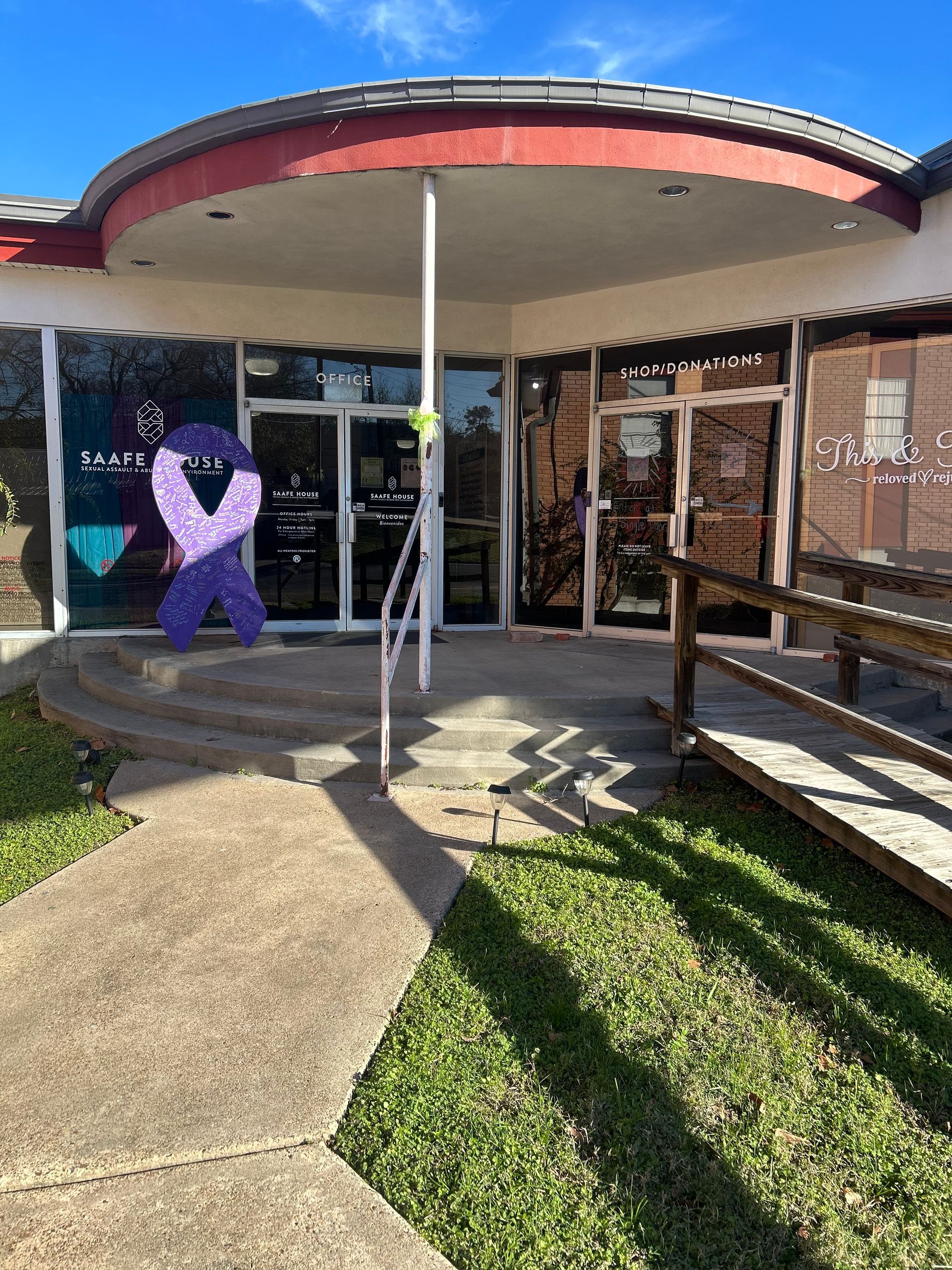Exterior of a building with glass doors, a purple ribbon, and a ramp for accessibility.