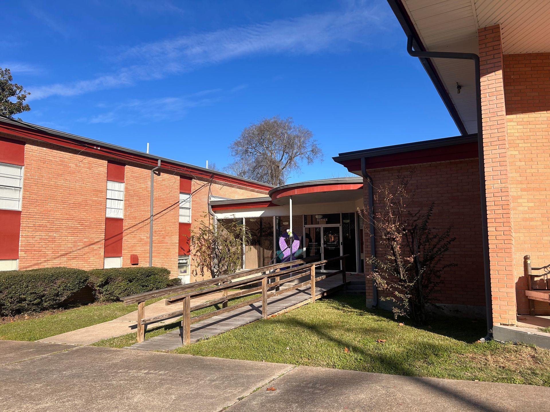 Brick building with a wooden ramp leading to a doorway. Bright sky.