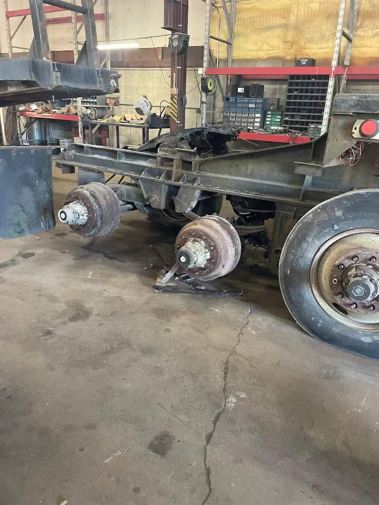 A red truck is parked in a grassy field next to a red car.