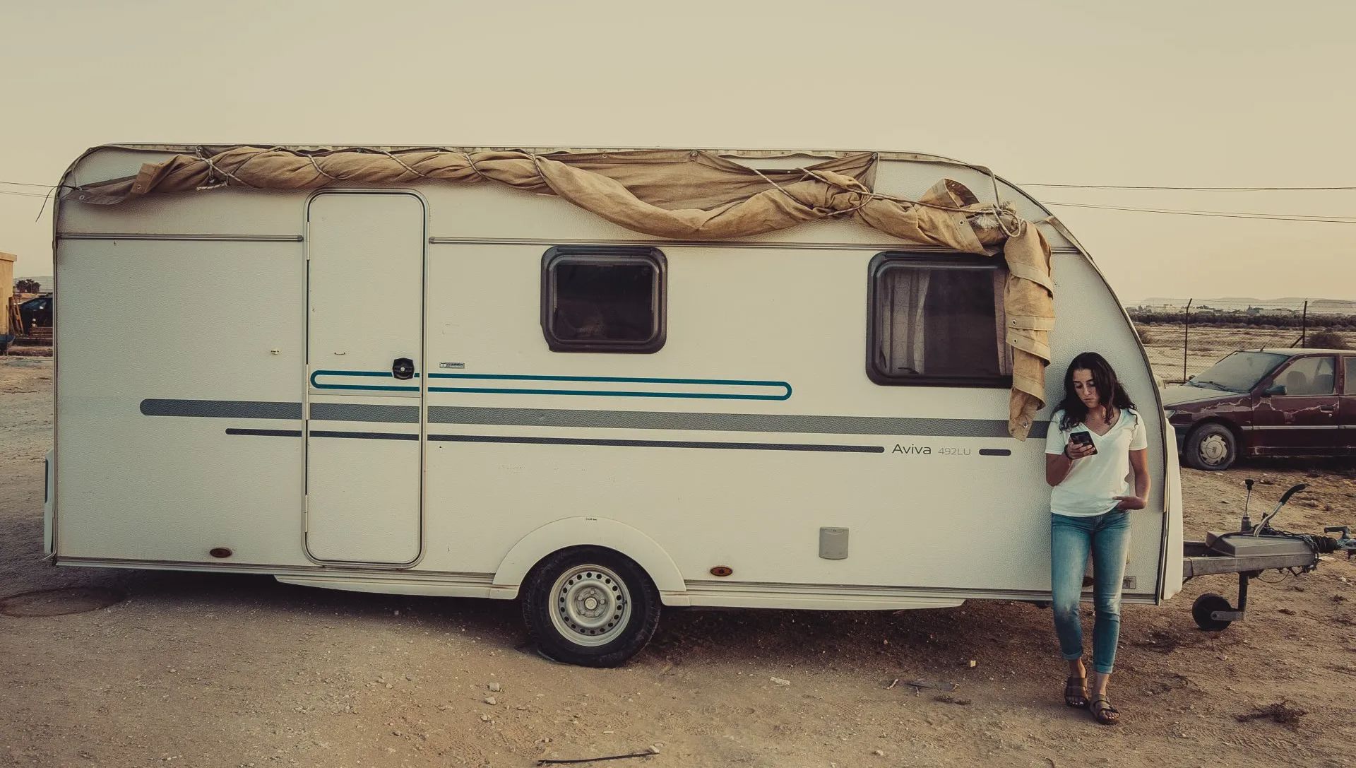 woman standing outside RV looking at phone