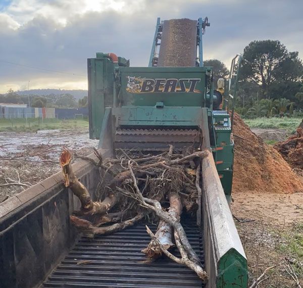 A pile of wood is being processed by a machine in a field.