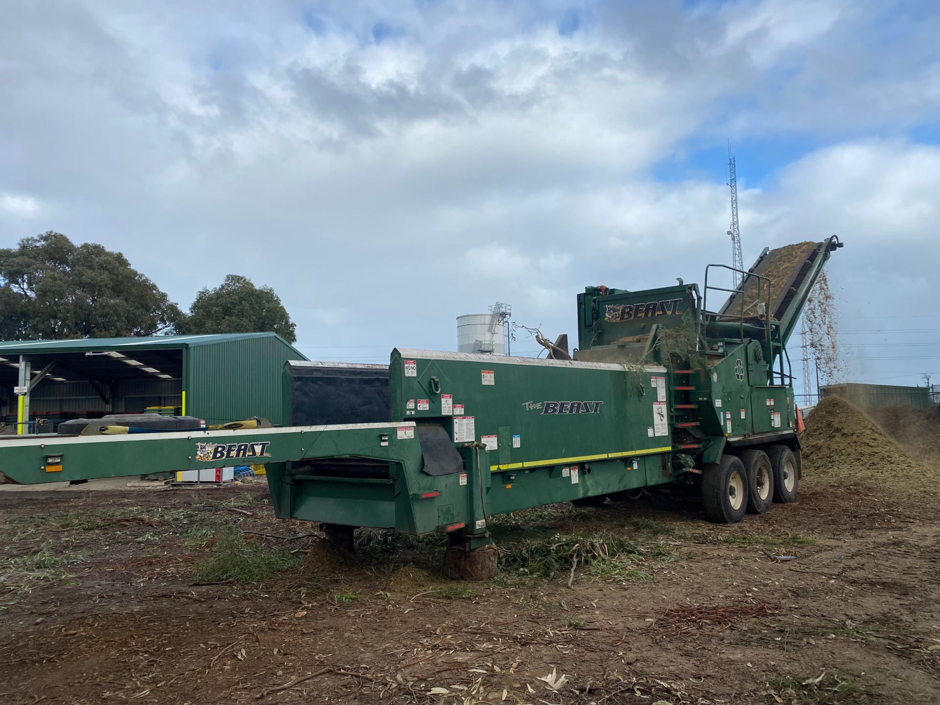 A large green machine is parked in a dirt field.