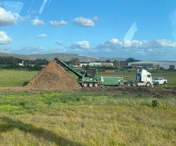 A truck is carrying a pile of dirt in a field.
