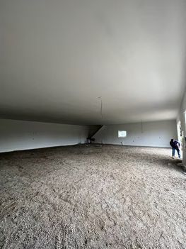 Spacious, empty room with a high, white ceiling and a dirt floor