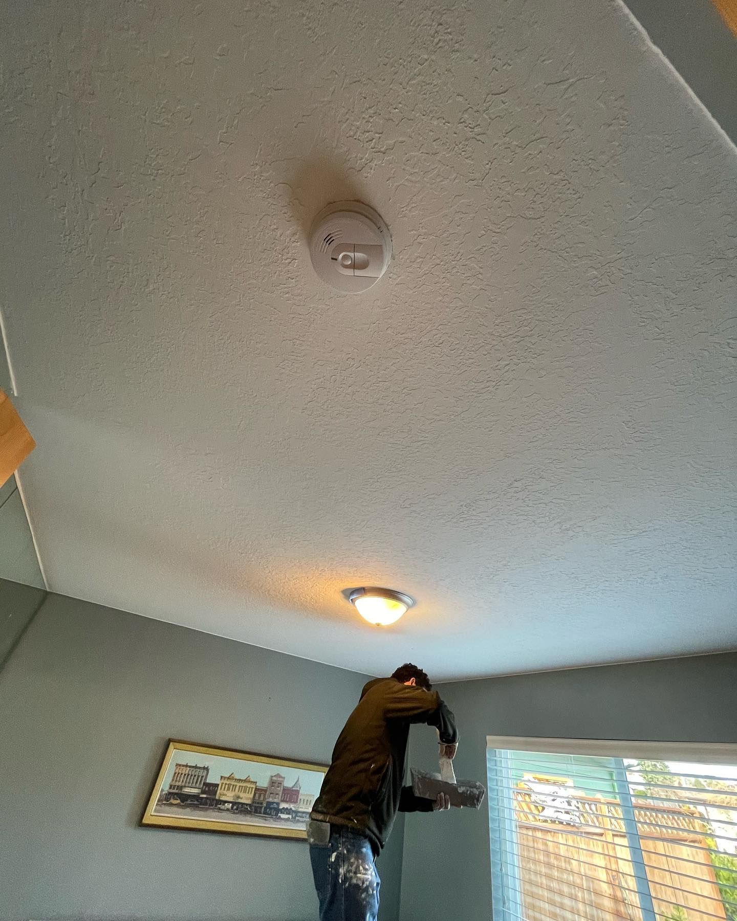 Person on a ladder painting a ceiling with a roller Person on a ladder painting a ceiling with a roller