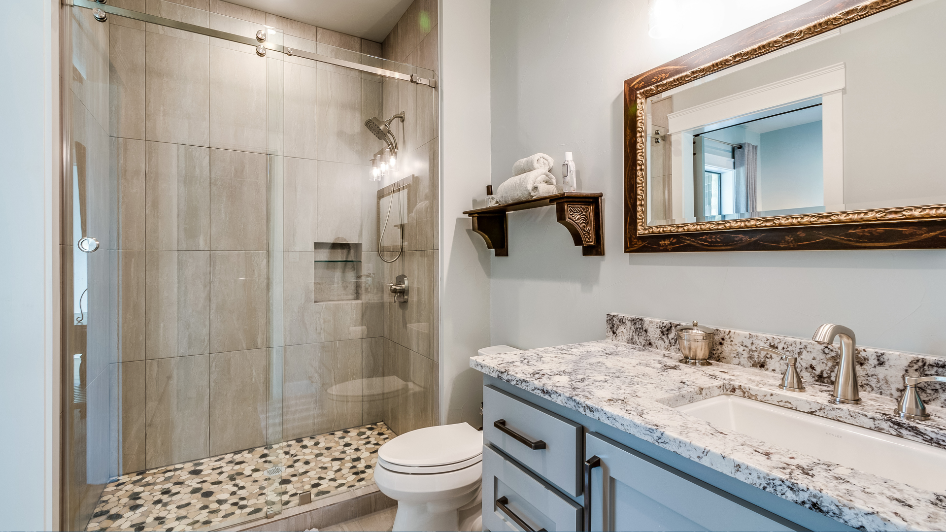 A bathroom with a toilet , sink , mirror and walk in shower.
