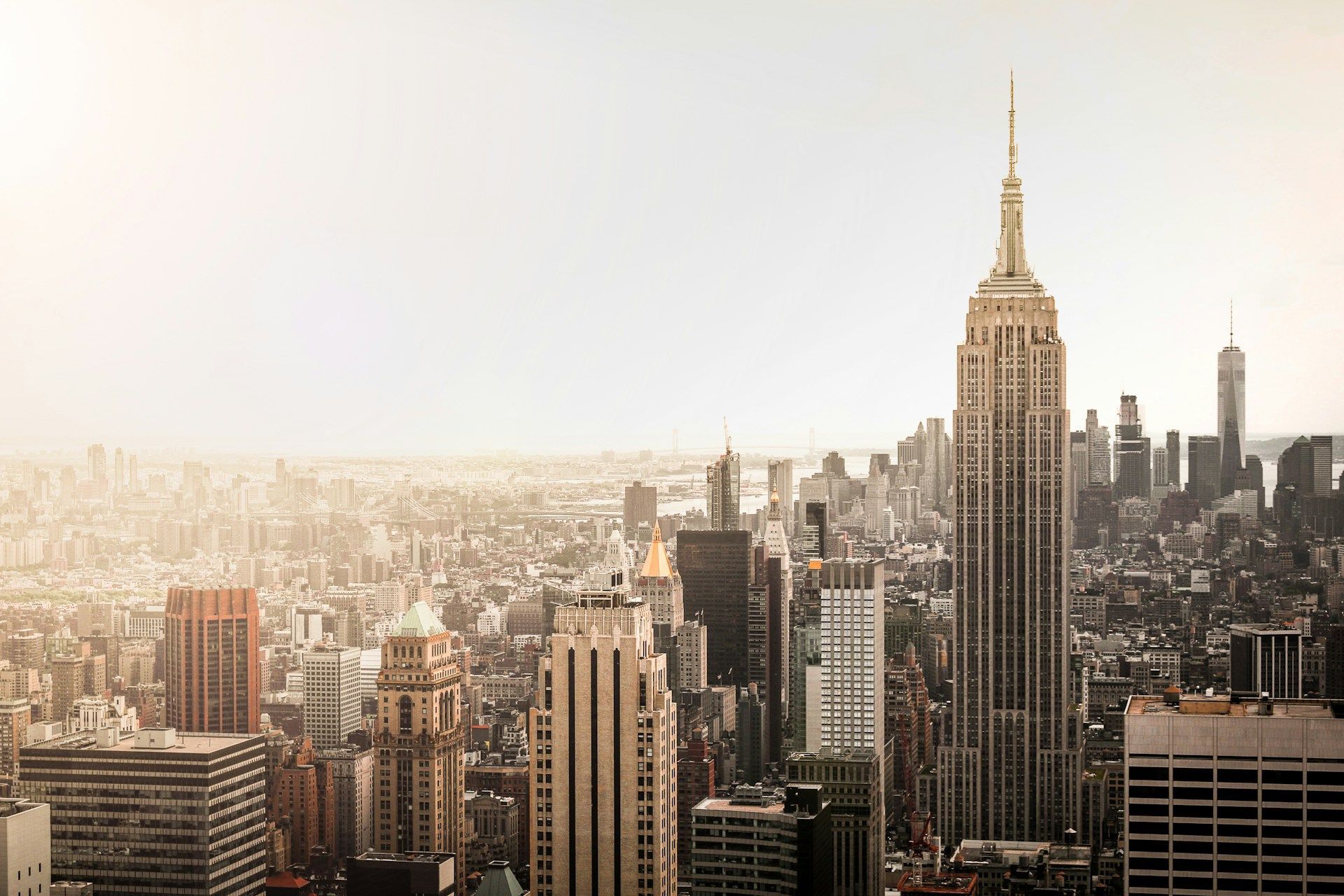 New York City skyline with the Empire State Building prominent, under a hazy sky.
