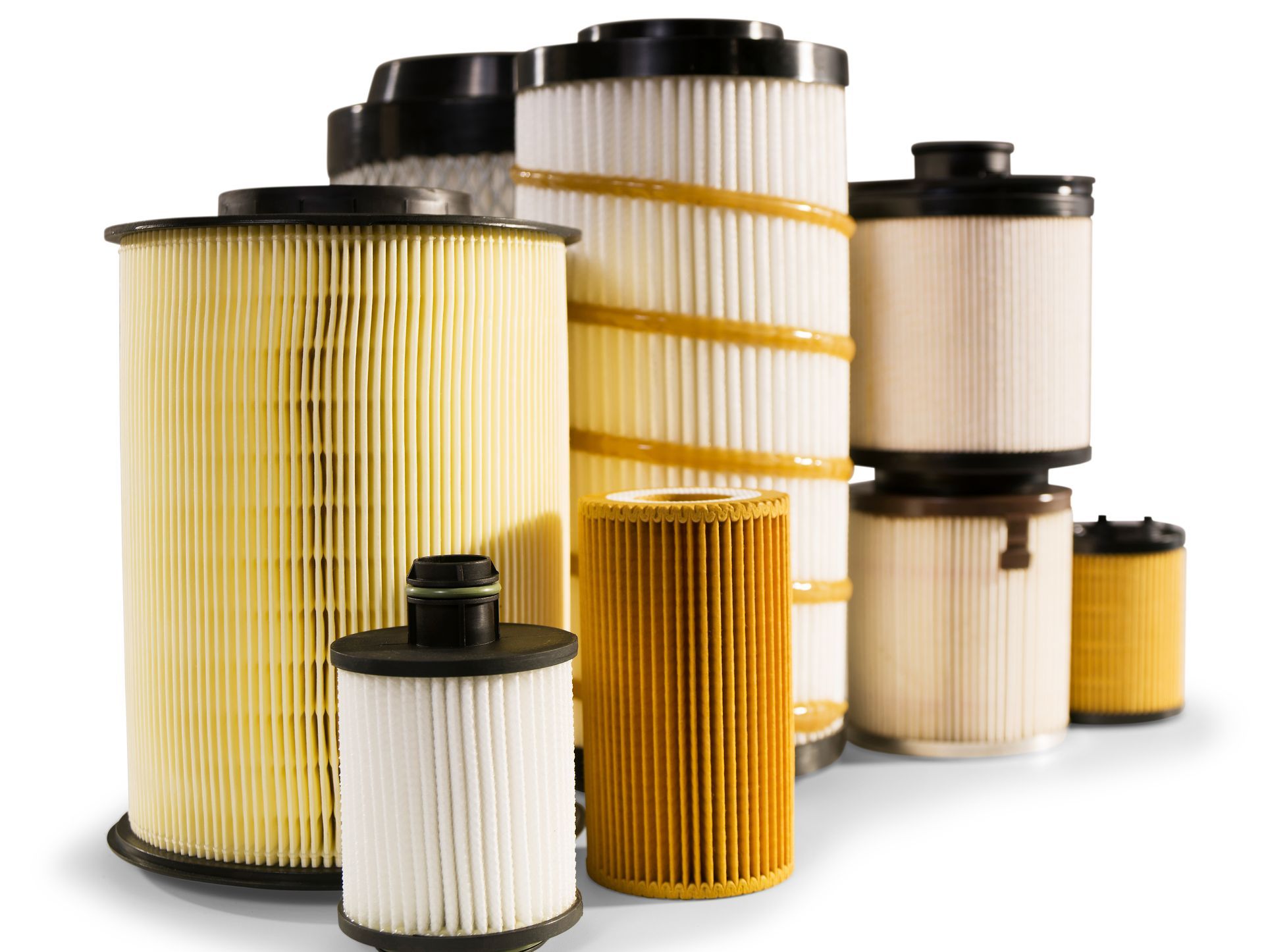 Assorted automotive air and oil filters, cylindrical with pleated paper, in various sizes.