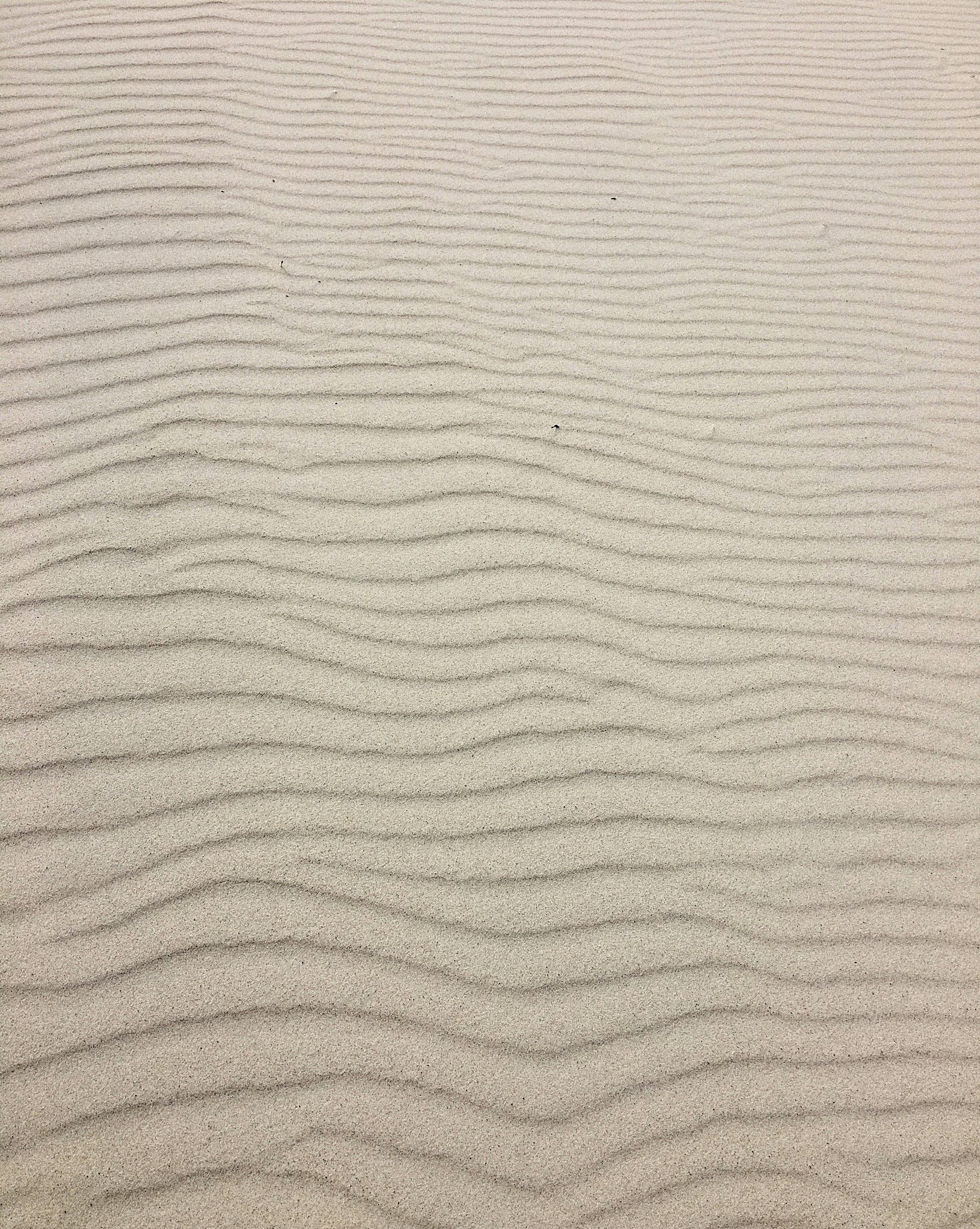 Sand with wave-like patterns, beige color.